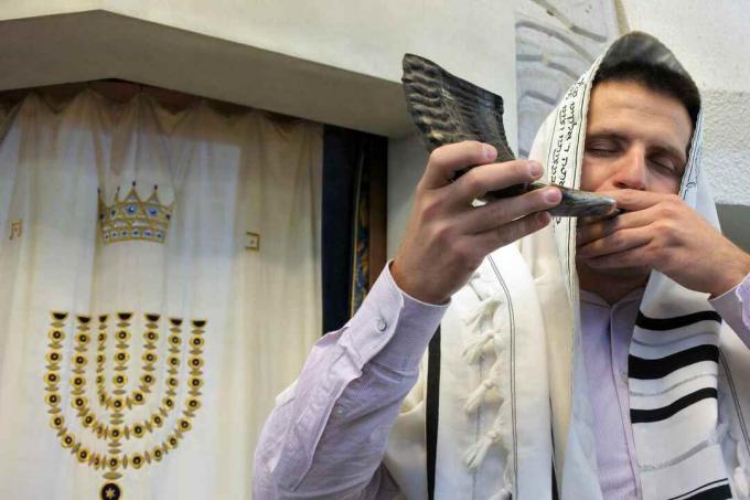 Jødisk rabbiner blåser shofar i en synagoge