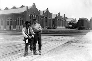 To servicemenn står ved siden av Pullman Building og trener biler med låste armer og en flaske brennevin under Chicago Pullman Strike i 1894