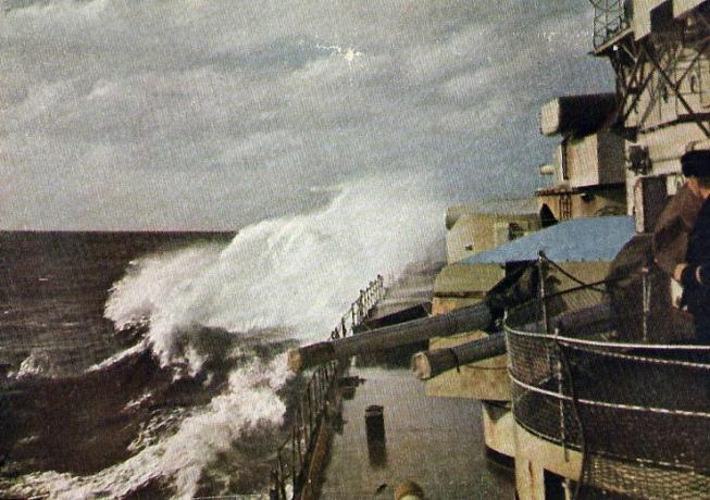 Utsikt over Scharnhorts som ser frem langs babord siden bølger krasjer over baugen.