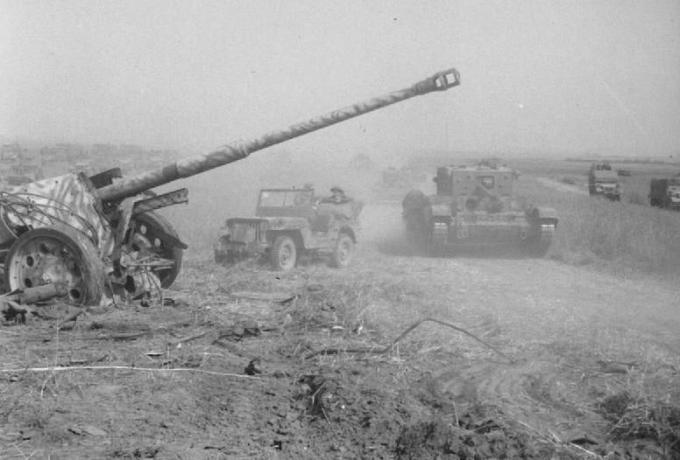 Britisk tank avanserte forbi en ødelagt tysk feltpistol.