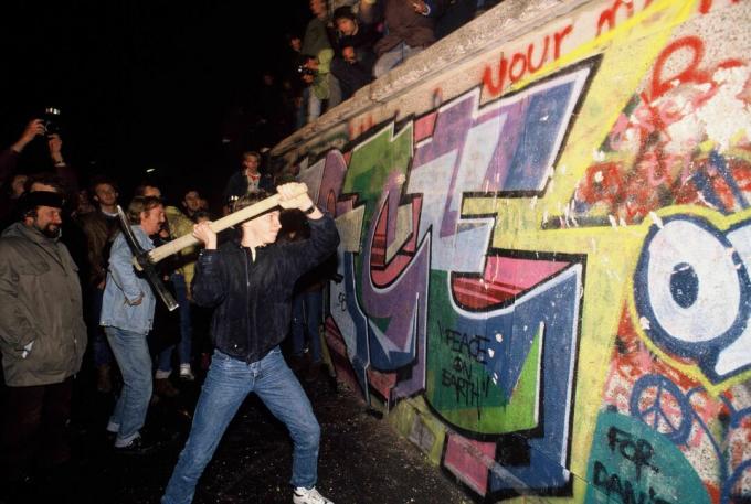 En mann angriper Berlinmuren med en pickaxe natt til 9. november 1989