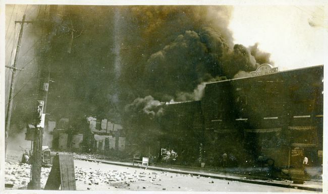 Skadede eiendommer og røyk som kommer fra bygninger etter Tulsa Race Massacre, Tulsa, Oklahoma, juni 1921.