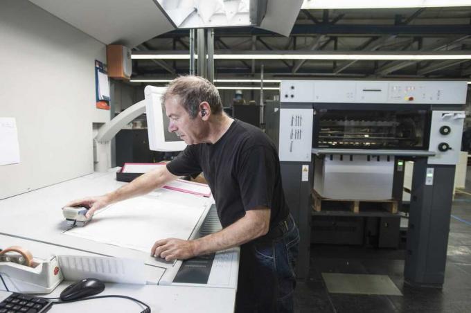 Arbeider som forbereder digitalt trykkutstyr i trykkverksted
