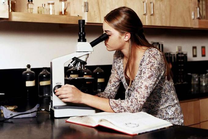 Tenåringsjente (14-16) bruker mikroskop i vitenskapslaboratoriet