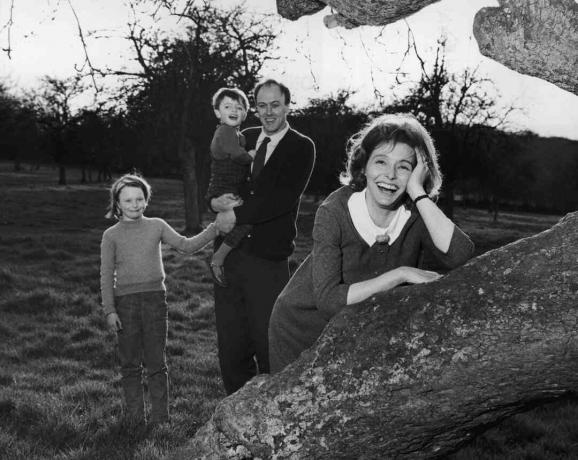 Svart / hvitt foto av Roald Dahl som holder barna sine; kona Patricia Neal lener seg på et tre
