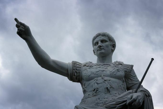 Statue av Julius Cæsar mot en stormfull himmel.