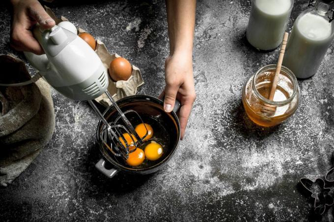 Person som slår egg på et bord med melk og honning