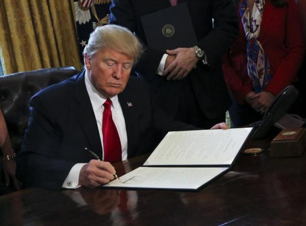 USAs president Donald Trump signerer utøvende ordrer, inkludert en ordre om å gjennomgå Dodd-Frank Wall Street for å rulle tilbake økonomiske reguleringer fra Obama-tiden.
